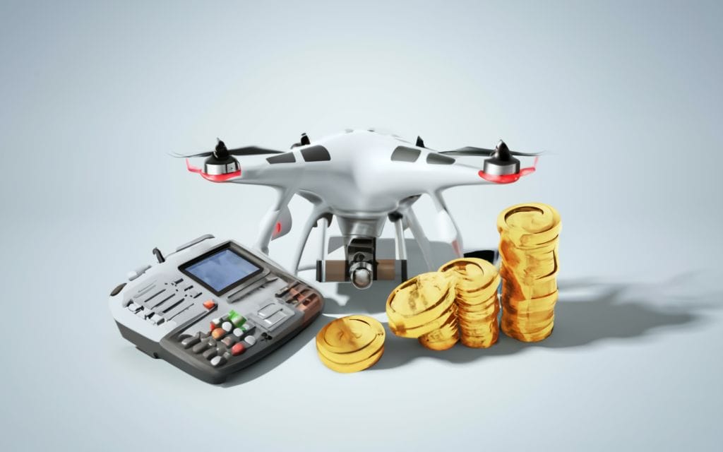 An image of a drone and coins next to a remote control. Pertinent to 'drone pilot salary'.